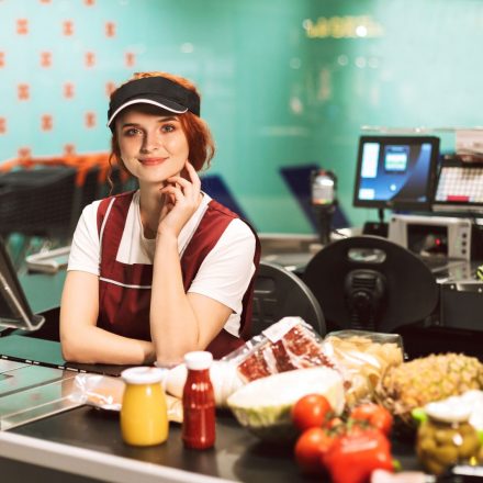 young-smiling-female-cashier-in-uniform-dreamily-Z74XGMA.jpg